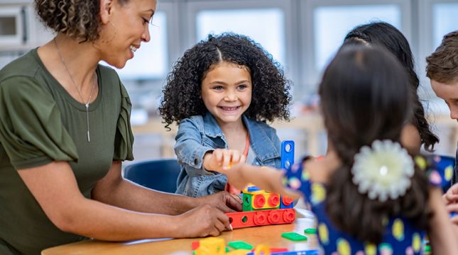 有幼儿园年迈的学生的老师在桌子的一个项目